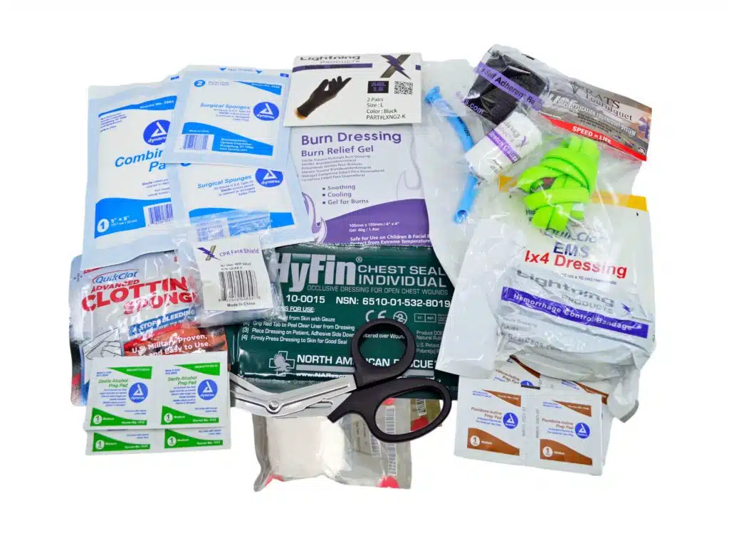 Flat lay of trauma kit contents including chest seal, burn dressing and shears