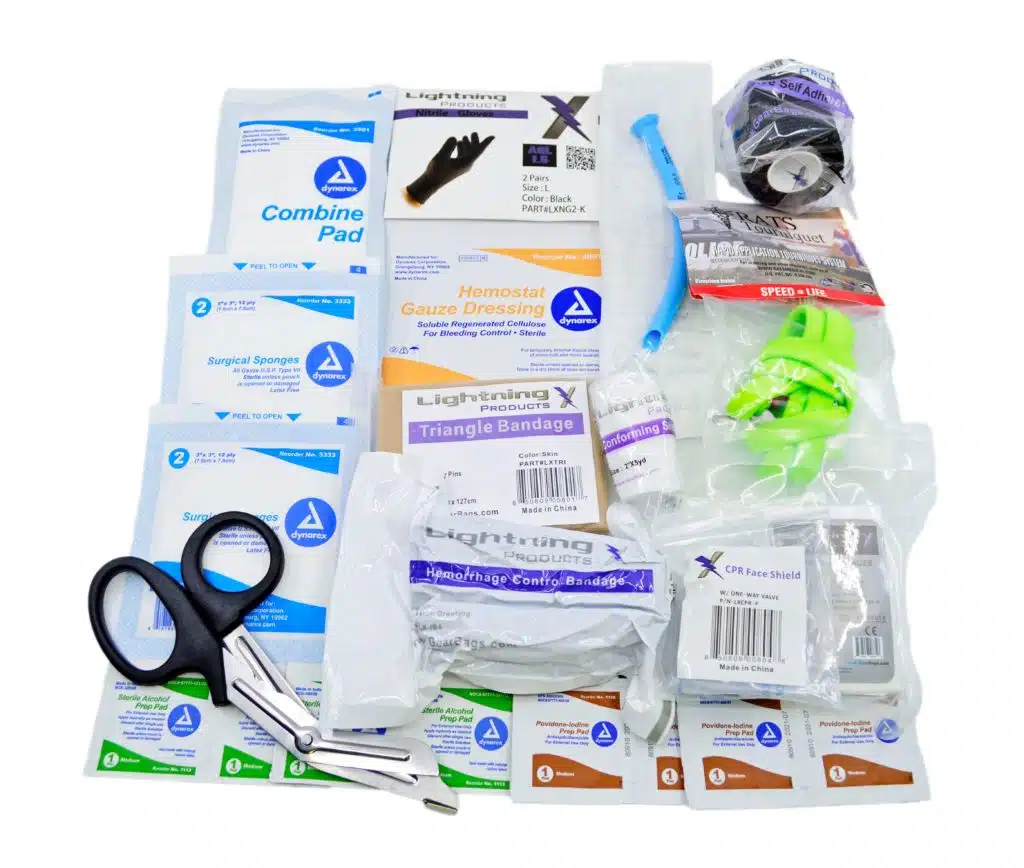 Flat lay of first aid kit contents with trauma shears, gauze and combine pads