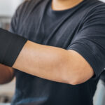 man wrapping his injured arm with lightning x black self adherent bandage wrap