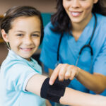 nurse or doctor office wrapping injured child's arm with lightning x black self adherent bandage wrap