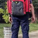 Person wearing a red and black tactical EMS backpack outdoors