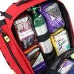 oxygen tank and colored pouches arranged inside red trauma backpack