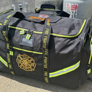 Angled front view of large black gear bag laying on concrete