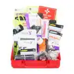 Red hi-vis hard-case first aid kit open, supplies organized in compartment trays under a translucent yellow lid