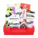 Red hi-vis hard-case first aid kit open, supplies organized in compartment trays under a translucent yellow lid