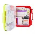 Red hi-vis hard-case first aid kit open, supplies in dual-layer swing-out trays under a translucent yellow lid