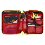 Red soft-shell first aid kit opened flat, revealing color-coded pouches and supplies in labeled mesh pockets