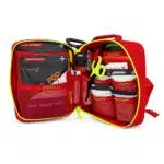 Red soft-shell first aid kit laid open, showing organized medical supplies in labeled mesh pockets and loops