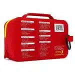 Red waterproof first aid case, angled back view showing the printed contents list and a black carabiner clip